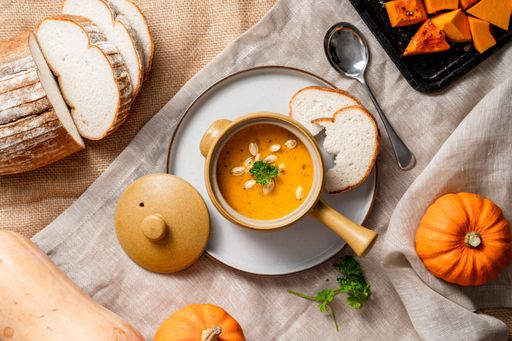 A top view of pumpkins and squashes, with pumpkin soup and bread