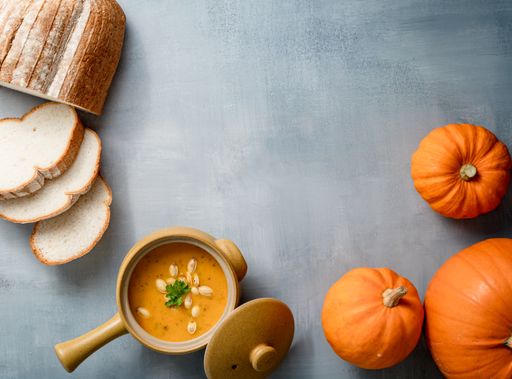 A top view of pumpkins and squashes, with pumpkin soup and bread