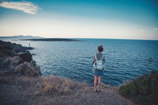 A back view of the female standing near the sea