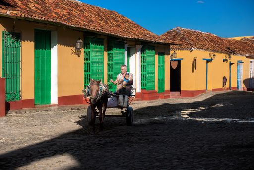 Horse drawn carriage transporting a grandfather and his grandson through the cobblestone streets of Trinidad, Cuba.