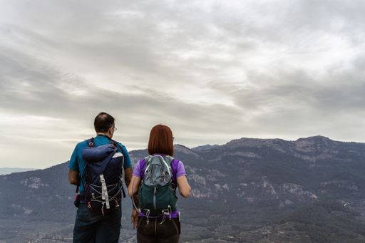 A touristic couple with backpacks standing in front of scenic mountains