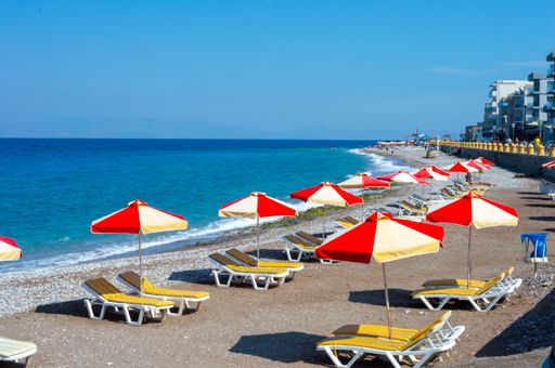 The sun loungers with red and yellow umbrellas at the Akti Kanari Beach in Rhodes Greece