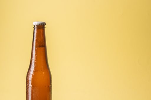 A closeup of the beer bottle on a red background.