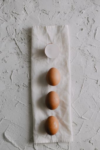 A high angle shot of eggs and eggshells on a white towel on the table