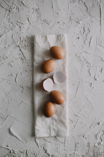 A high angle shot of eggs and eggshells on a white towel on the table