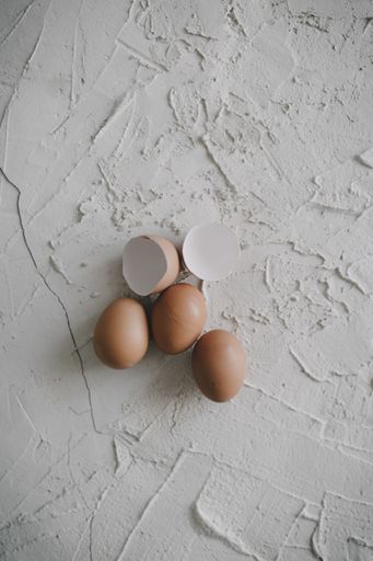 A vertical shot of eggs and eggshells on a white surface