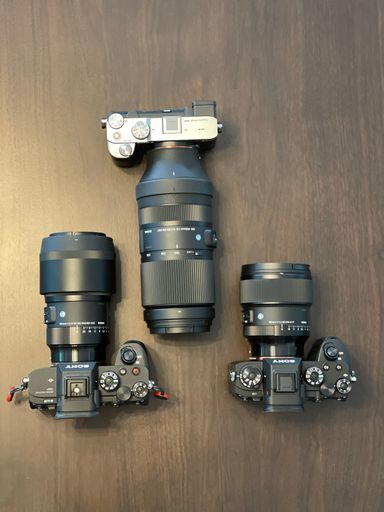 A top view of a collection of cameras and lenses on a wood table.