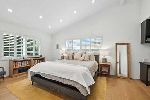 An interior design of a modern bedroom with a king size bed and a TV on the wall