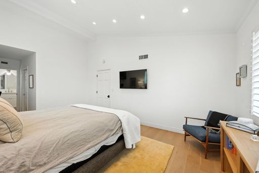 An interior design of a modern bedroom with a king size bed and a TV on the wall