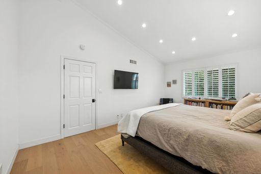 An interior design of a modern bedroom with a king size bed and a TV on the wall
