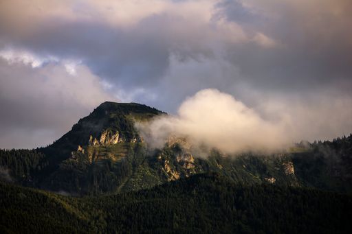 A breathtaking view of mountain peaks under a cloudy sky covered with clouds