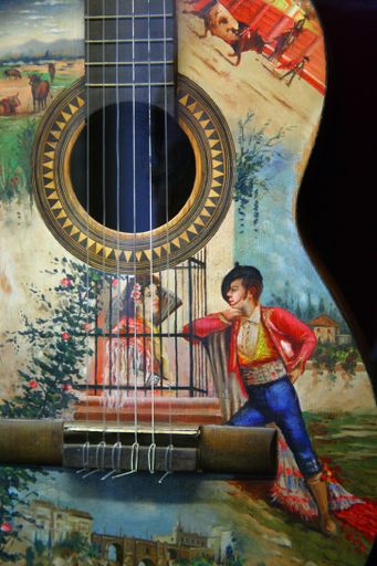 A vertical shot of art on the body of a guitar with a black background