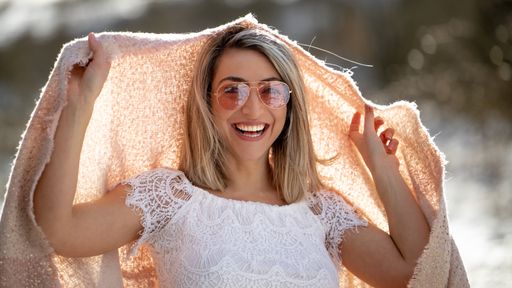 A closeup of a beautiful blonde woman with sunglasses and a smile on her face.