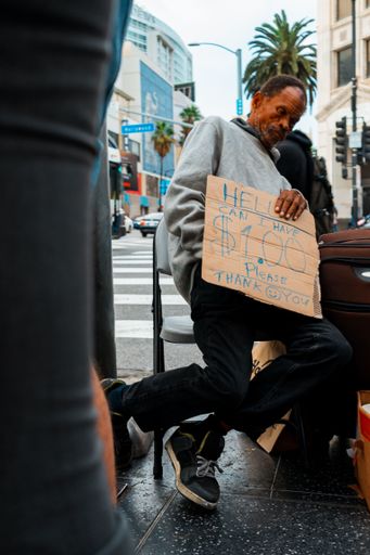 The vertical shot of an homeless black elder man homeless person holding a sign asking for money