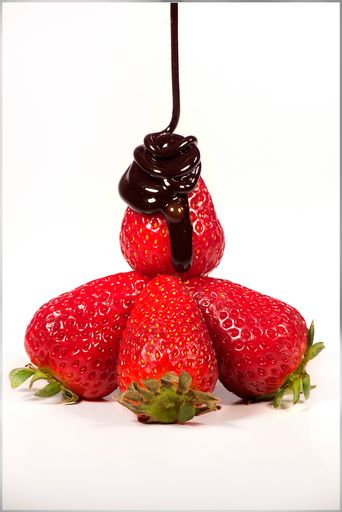 A vertical shot of fresh strawberries with chocolate sauce on a white background