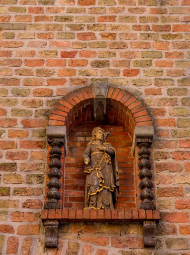 A vertical shot of a statue on a brick wal in lBelgium, Bruges