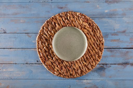 A top view of an empty ceramic plate on wicker
