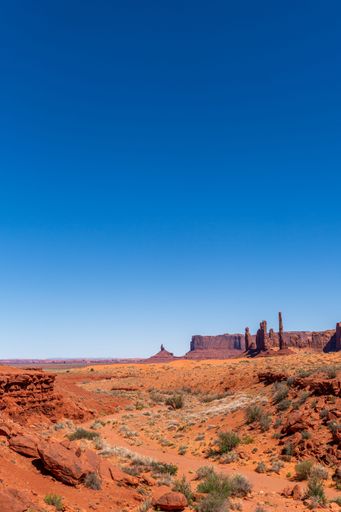 A stunning view of Monument Valley's iconic red rock formations under a clear blue sky, showcasing the beauty of the American Southwest.