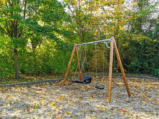 A closeup of an empty swing against forest trees