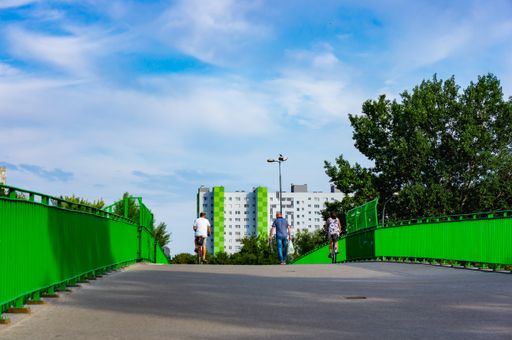 A group of people on a bridge with green barriers in the Orla Bialego district, Poland