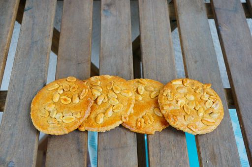 A high angle shot of fresh delicious golden peanut cookies placed on wooden planks