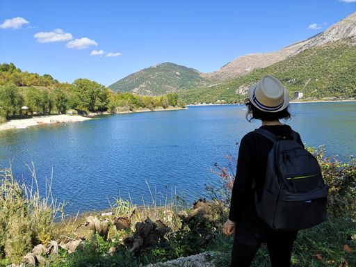A rear view of a female tourist looking at the Lake Pio in Villalago Abruzzo, Italy