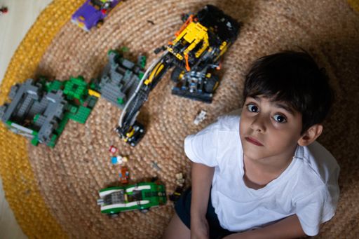 An overhead shot of a Caucasian boy with toys in his room