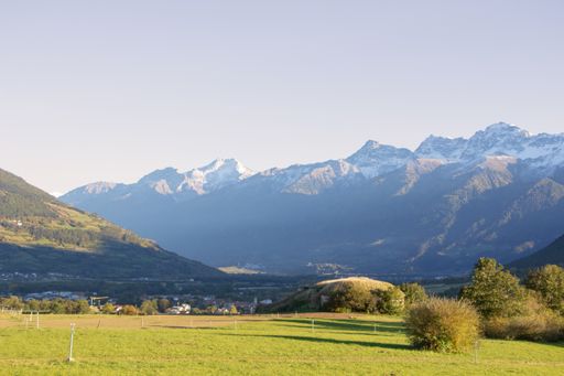 A natural view of a vast greenfield against mountain landscape on a sunny day
