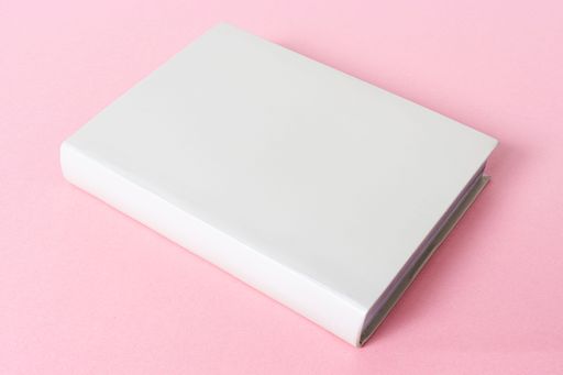 Closed generic blank book isolated on pink background. Template mock up