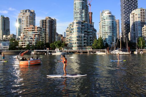 The people with paddles on surfs on water against skyscrapers in Vancouver, British Columbia, Canada