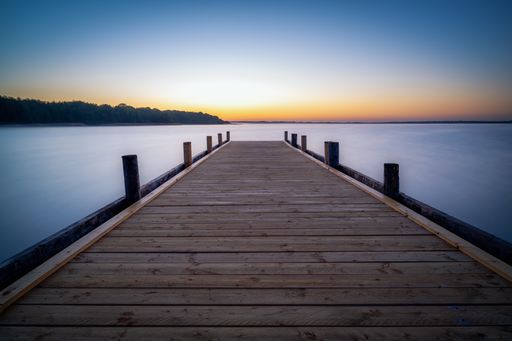 A wooden dock on Lake Steinhude with long exposure during the sunrise in Germany