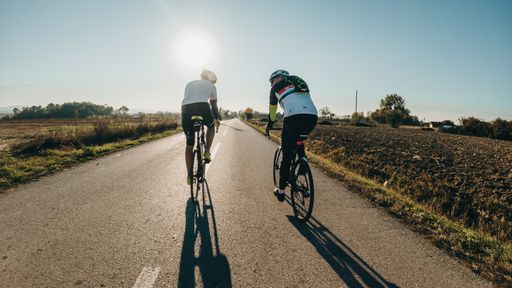 A road in the countryside with two guys on bicycles riding into the sun, in Bijeljina, Bosnia and Herzegovina