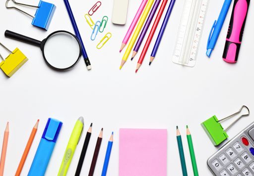 A top view of stationery isolated on a white background. The magnifying glass, calculator, pencils, markers, ruler, and clips