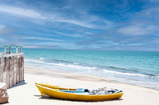 An abandoned boat rests on a beach in Aguada, Puerto Rico, under the daytime sun.