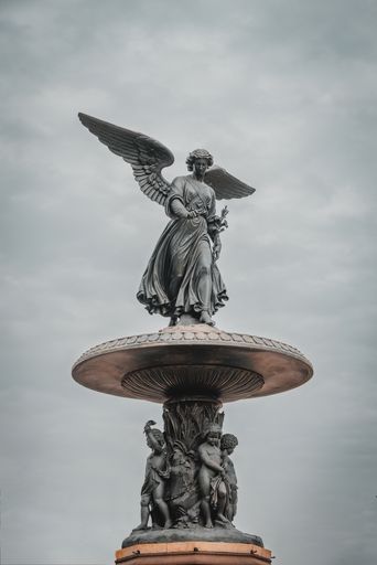 A vertical shot of Bethesda Fountain under a dark cloudy sky in Central Park New York City