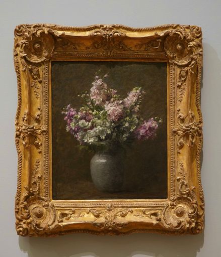 A classic still life painting of a floral arrangement in a vase, encased in an ornate golden frame, displayed on a gallery wall.