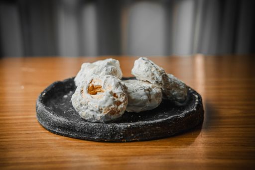 Close-up of powdered sugar-coated cookies on a rustic plate, set on a wooden table, creating a cozy and inviting atmosphere.