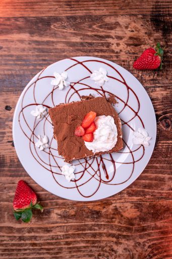 An overhead shot of a chocolate biscuit with whipped cream and strawberry