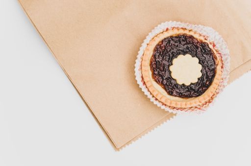 isolated cherry jam tart in a paper backing cup on a white background with text space