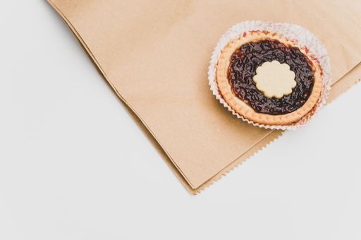 isolated cherry jam tart in a paper backing cup on a white background with text space