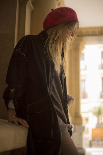 A young blonde female in a red beret posing with a pensive look in the city of San Sebastian, Spain