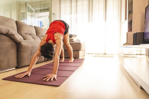 A brunette woman doing yoga exercises at home during the coronavirus quarantine