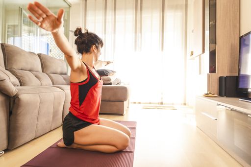 A young woman doing yoga and meditating at home during the coronavirus quarantine