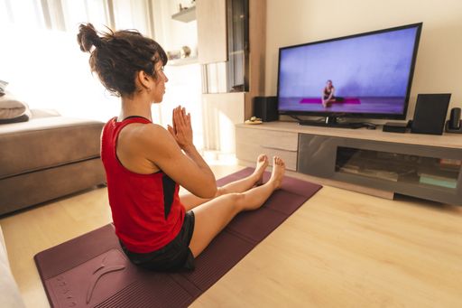 A young woman doing yoga and meditating at home during the coronavirus quarantine