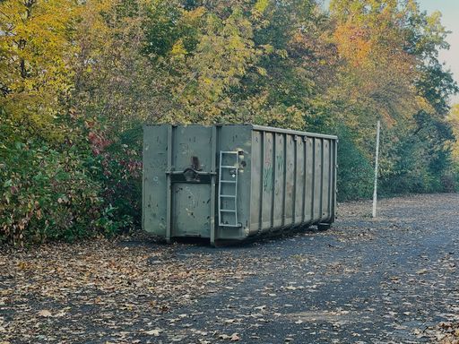 A large rubbish container is parked in a car park.
