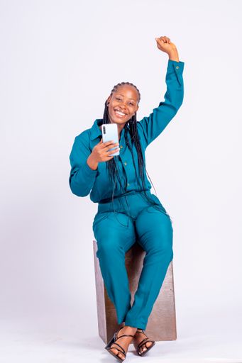 A vertical shot of a happy young African woman with a smartphone isolated on white background.