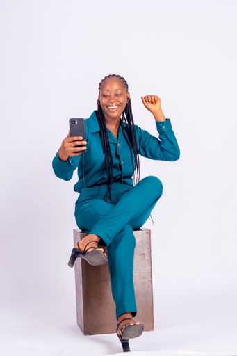 A vertical shot of a happy young African woman with a smartphone isolated on white background.