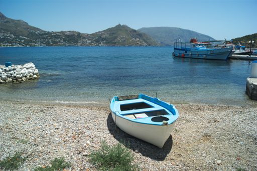 A small boat on the shore and boats in the lake