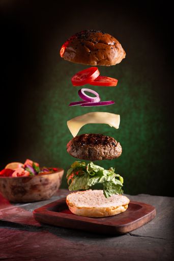 A vertical shot of a delicious burger with floating ingredients