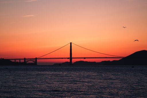 A wide distant shot of the Golden Gate Bridge on the body of water during sunset in San Francisco, California